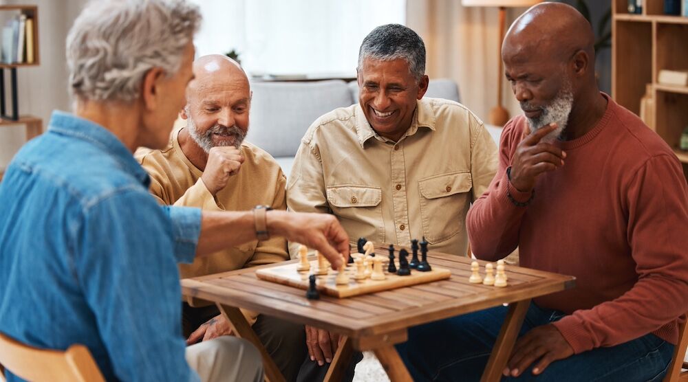 Four senior men play chess and board games at one of the best San Diego retirement communities