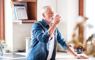 Senior man drinking water in the kitchen