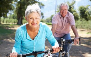 A happy, healthy senior couple ride bikes around their senior living community in San Diego