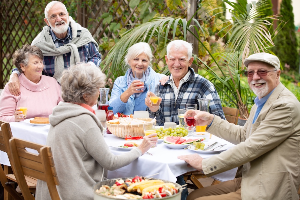 Group of senior residents dining outside and enjoying their independent senior living